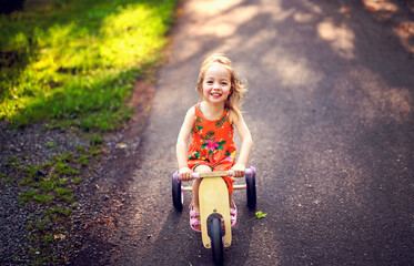 happy child girl rides a racetrack in Park in the summer sunset