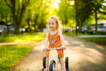 happy child girl rides a racetrack in Park in the summer sunset