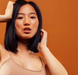 Fototapeta premium young pretty asian woman cheerful smiling posing on warm brown background, lifestyle people concept