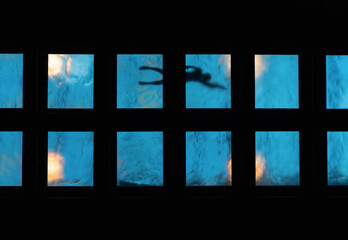 view from below of a silhouette of a person swimming in a pool with glass floor