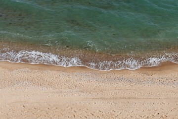 Beach on aerial drone top view with ocean waves reaching shore, top view photo of an amazingly beautiful sea landscape.