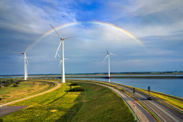 Fototapeta na wymiar Wind turbines rotate against the backdrop of a rainbow