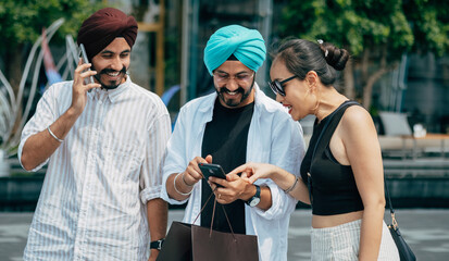 Group Of Smiling Friends Having Fun While Using Mobile Phone At The City Street