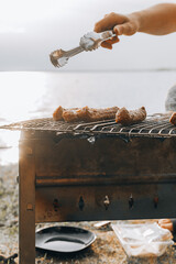 Close up unrecognizable man hands smoked pork meat on outdoor barbecue. Chef putting juicy sausage on grill in forest park outdoor. Preparing dinner lunch Eating summer food in backyard countryside.