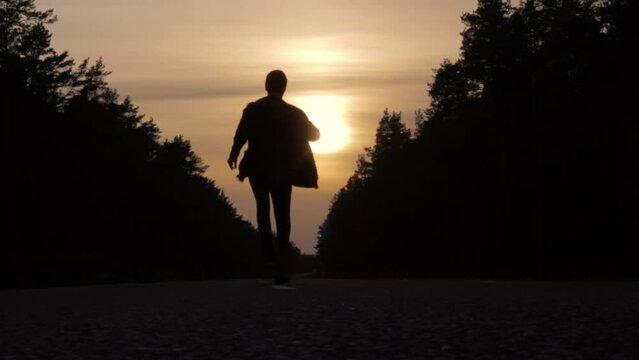 Silhouetted man persuing aspiration dreams, running away middle of road