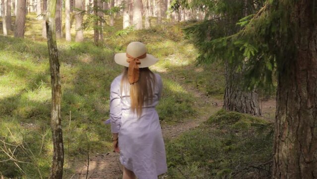 Single girl walks away wandering through woods forest path, summer activity