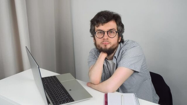 Portrait of disabled man in glasses with amputated two stump hands studying on laptop at home, distance education. Problem of adaptation to life people with disabilities. Independent Invalid person.