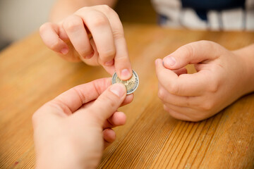 Adult giving coin to a child as saving money concept. Children's financial education, financial literacy. Payment for duties performed.