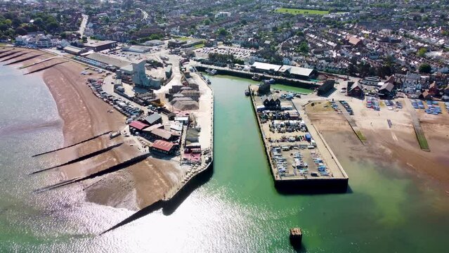 A dolly backwards aerial view of Whitstable Harbour, with a calm sea.