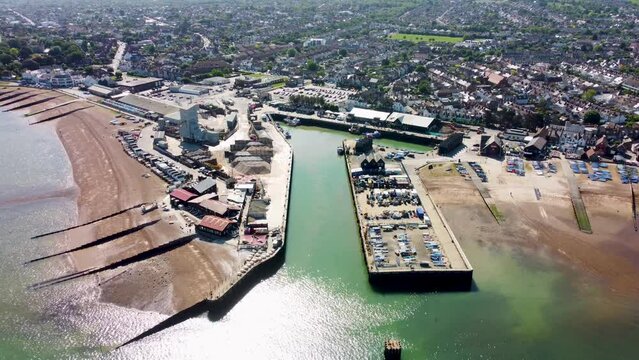 A dolly backwards aerial view of Whitstable Harbour, with a calm sea.