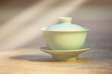 Gaiwan on the marble floor is a selective focus in the rays of the sun. Gongfu cha tea ceremony. Chinese ceramics of Zhu Yao. Chinese porcelain. Gaiwan tea cup and lid. Tea bowl with lid. Puer.