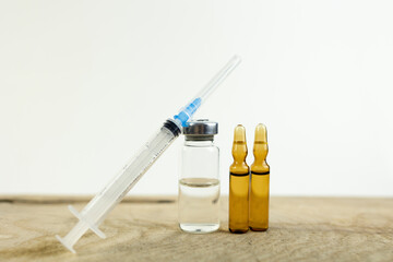 Medical background. Ampoules with a vaccine or medicine and a syringe on a wooden table. Medicine...