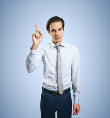 Warning concept wih young handsome man in white shirt with raising hand and forefinger isolated on light blue wall background, closeup