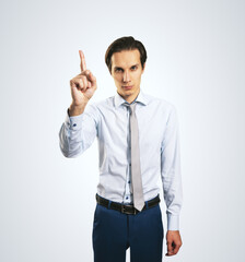 Warning and notification concept with young man with rising up index finger isolated on light grey wall background, closeup