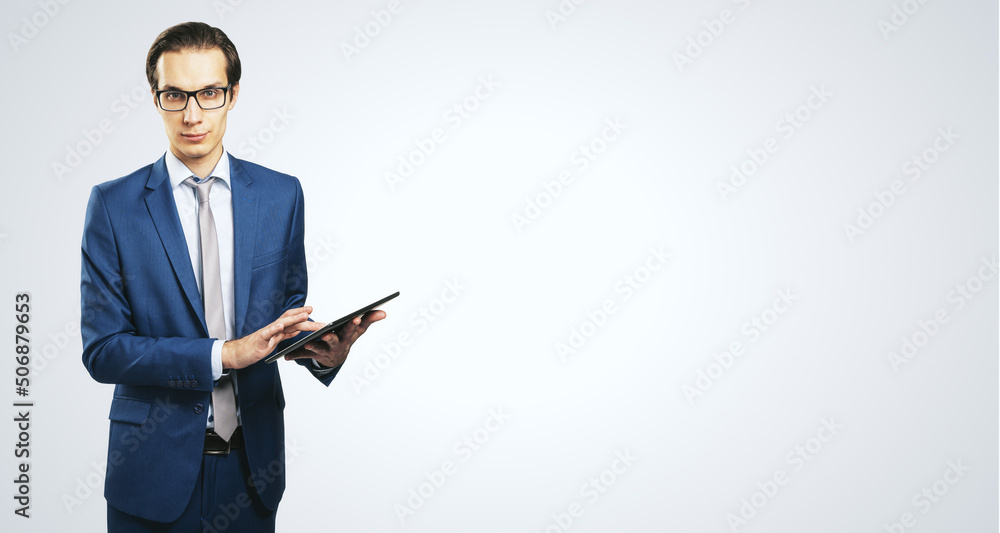 Poster young businessman in glasses and suit with digital table on white background with copyspace for your