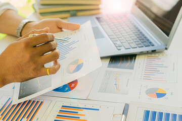Close-up of businessman holding pen pointing to graph graph in document Corporate financial marketing, research, development, planning, management, strategy, analysis, business office concept.