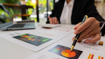 Close-up of businessman holding pen pointing to graph graph in document Corporate financial marketing, research, development, planning, management, strategy, analysis, business office concept.
