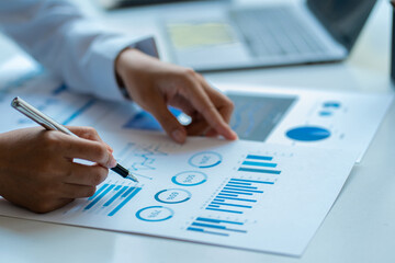 Close-up of businessman holding pen pointing to graph graph in document Corporate financial...