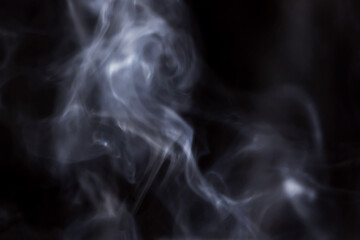 Smoke rises in the air on a black background.