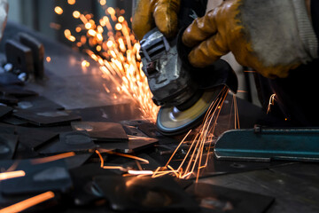 Grinding metal plates with electric wheel in factory. Sparks from the grinding wheel. Selective...