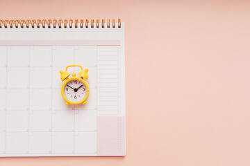 Planner and alarm clock on the pink background, planning for business meeting or travel planning concept