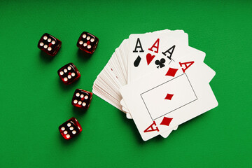 Stack of playing cards and red dice on a green table, casino concept.