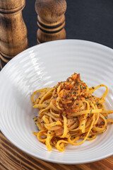 Homemade bolognese noodles with bacon and fried tomato along with ingredients used in the recipe such as tomato and oregano, with a rustic presentation of wooden plates and kitchen utensils