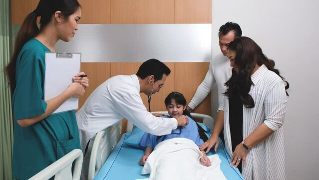 The doctor is examining a patient, a cute girl with her father and mother taking care of him.