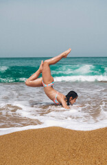 Chica practicando ejercicio en la orilla del mar con un bikini de colores.