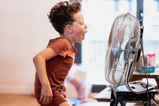 Little boy at home playing with fan