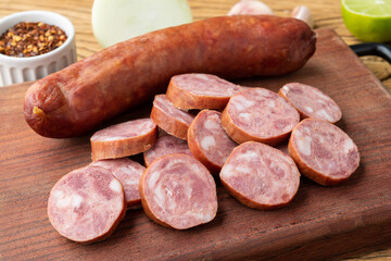 Calabrese pork sausage with slices over wooden board with seasonings