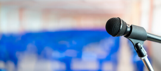 Microphone on abstract blurred of speech in seminar room or speaking conference hall light