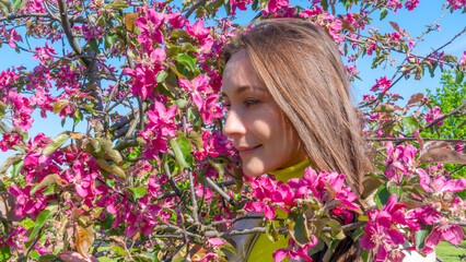 Fototapeta premium Portrait of beautiful young woman in paradise apple trees blooming park on a sunny day. Springtime. Red apple tree.