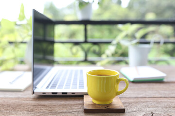 Yellow coffee cup an laptop side view