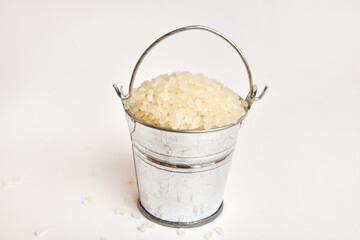Miniature metal bucket with rice on a white background.