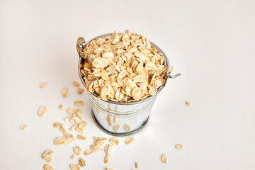 Miniature metal bucket filled with oatmeal on a white background.