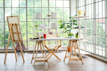 Decorations and several accesories in workplace for relax activity in room with glass window such as for painting, play music by guitar or read some books on shelves.