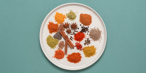 Various spices on a plate, turquoise pastel background. Top view, flat lay. Banner