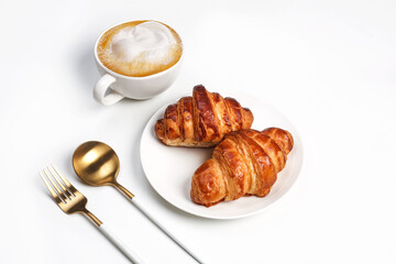 Morning breakfast setup on white surface. Flat lay of croissant, oranges, sourdough and coffee lying around.