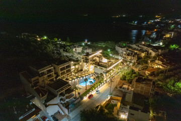 Fototapeta premium Beautiful hotel with palm trees, above view, in the night