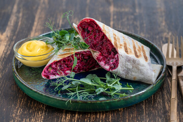 Vegan burrito. Sliced up raw food wrap with red beetroot, feta cheese, prunes, dill and cream sauce