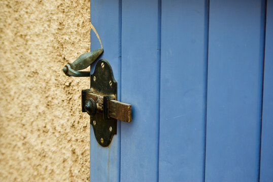 Yellow stone building with blue wooden shutter with locking device in Provence in France.