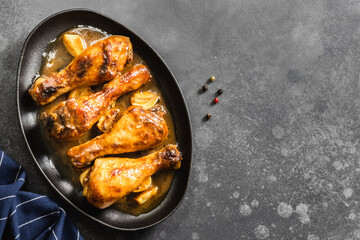 Teriyaki chicken legs in cast iron skillet on dark background. Top view, copy space.