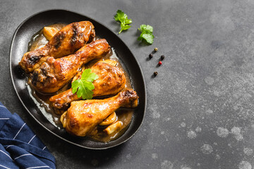 Oven baked soy sauce chicken legs in cast iron skillet on dark background. Top view, copy space.