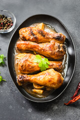 Honey mustard chicken legs in cast iron skillet on dark background. Top view, copy space.
