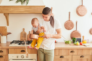 Solo dad with his son in his arms in the kitchen of the house.