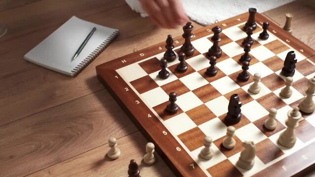 Women's hands make a move with a chess piece on a chessboard Girl playing chess holding with the benefit of free time The girl, an experienced chess player wrote down the move by a piece in a notebook
