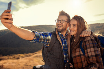 Couple with backpacks making selfie while they hiking on the mountain.