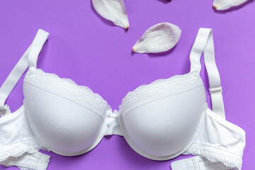 White new bra on a violet background. Bra, lace lingerie on a very peri  purple background. Beauty blog concept. Top view, flat lay 