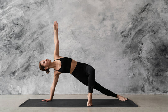 Young woman practicing yoga, copy space on the grunge textured wall